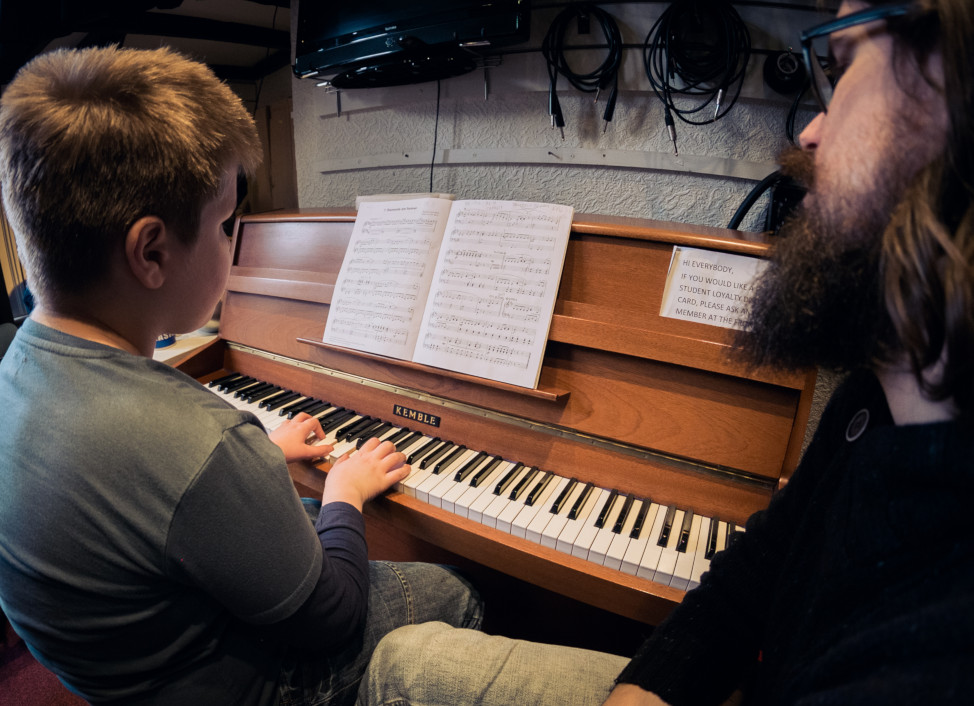 Boy having music tuition on acoustic piano.