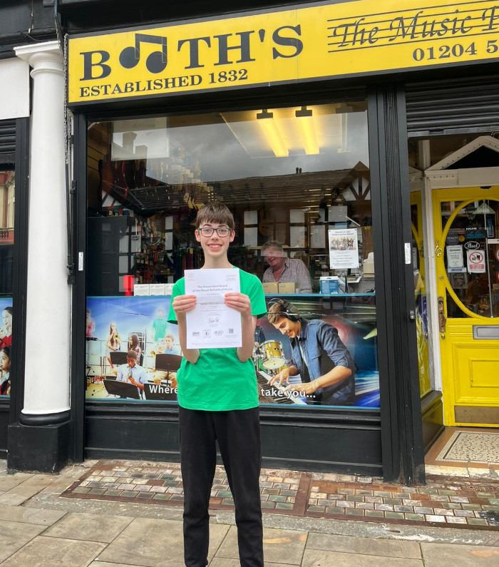 Thomas with his Certificate outside Booths Music