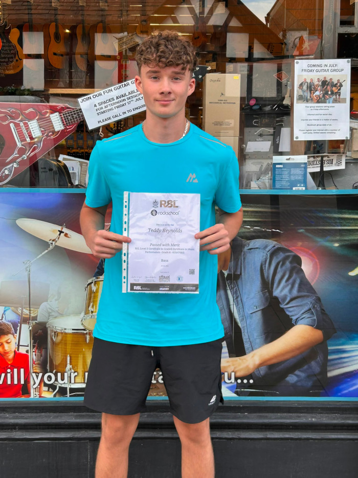 Teddy holding his Grade 8 Bass Certificate